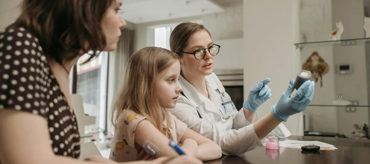 Mutter mit Kind beim Arzt während des Blutzuckertests